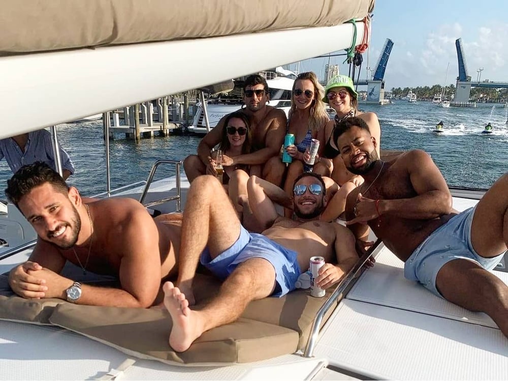 Group of young people enjoying a day sail on a deck of a sailing catamaran cruising the intracoastal in Fort Lauderdale Florida with Fun In The Sun Yacht Charters